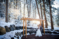 Bride and groom in the golden sunlight with snowcapped trees at their spring wedding