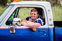 male senior posing in his truck and football jersey